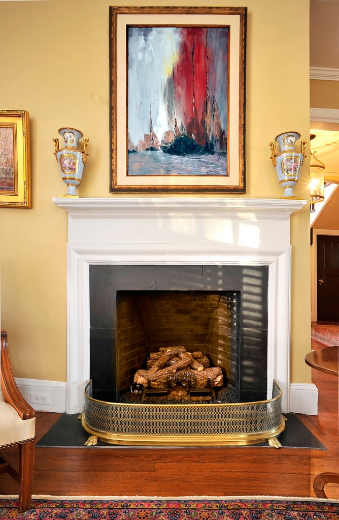 A refurbished white fireplace in one corner of the living room.