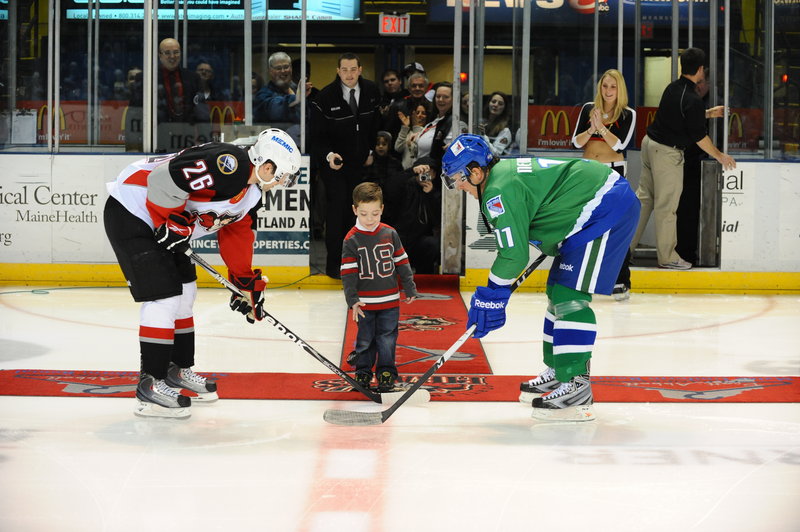 Colby Nadeau, 6, of Buxton drops the puck for the ceremonial faceoff between Portland Pirates forward Brian Roloff, left, and Kris Newbury of the Connecticut Whale before their game on Dec. 31. Nadeau, who has a severe form of childhood epilepsy called Doose Syndrome, is an avid Pirates fan and finally received his wish to play hockey.