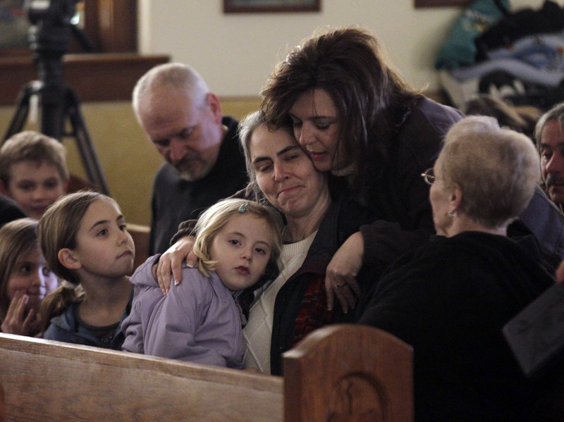 Residents attending Mass at St. Francis Xavier Catholic Church hug before the start of services in Henryville, Ind., on Sunday. The church was in the path of a tornado that destroyed much of the town.