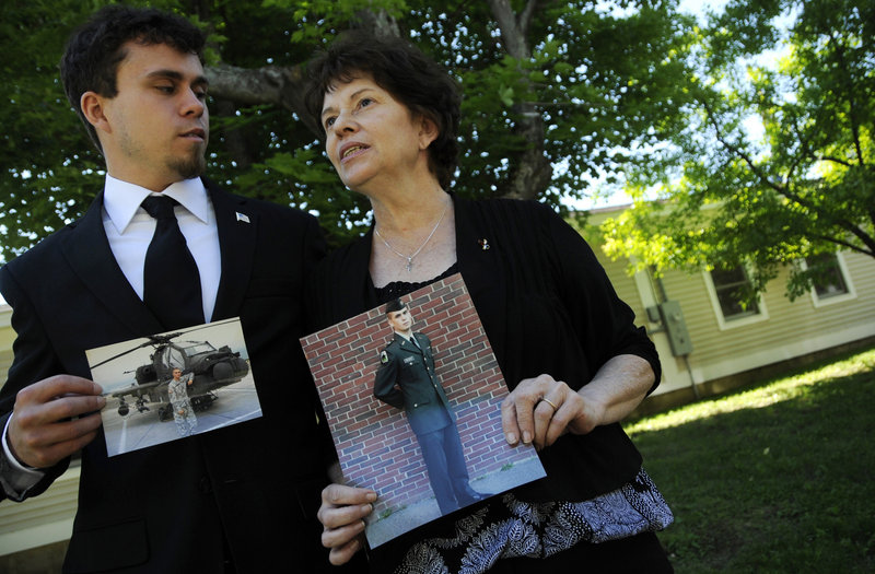 Susan Phelps, mother of Capt. John “Jay” Brainard III, and Benjamin Hawthorn, his stepbrother, pose with photos of Brainard near their home in Newport on Thursday.