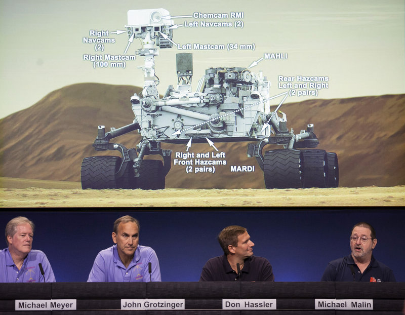 Scientists comment on the seven cameras aboard the Curiosity Mars Rover, background, during a media briefing Thursday at NASA’s Jet Propulsion Laboratory in Pasadena, Calif. Curiosity is scheduled to land on Mars at 1:31 a.m. Monday. Its target is the Gale Crater.