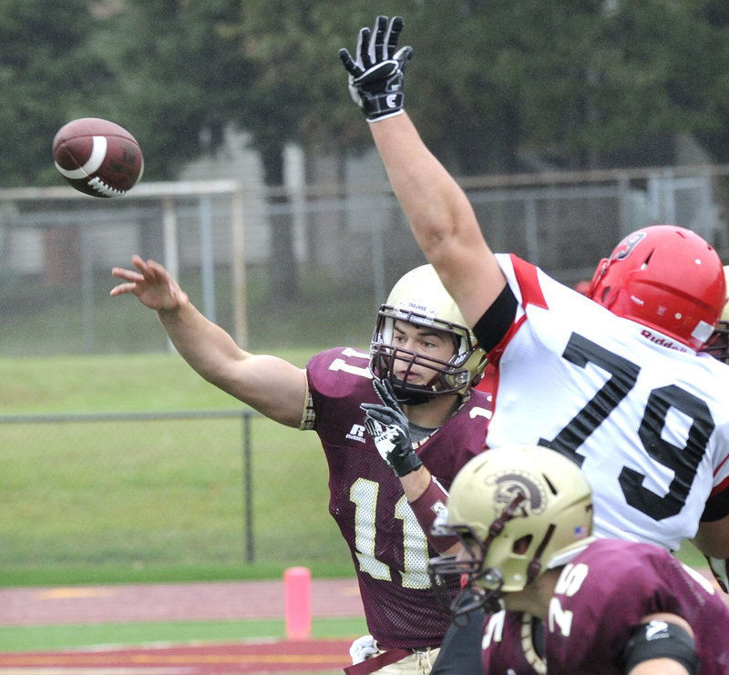 Thornton Academy quarterback Eric Christensen zips a pass as lineman Mike Pino of Scarborough attempts to bat it away.