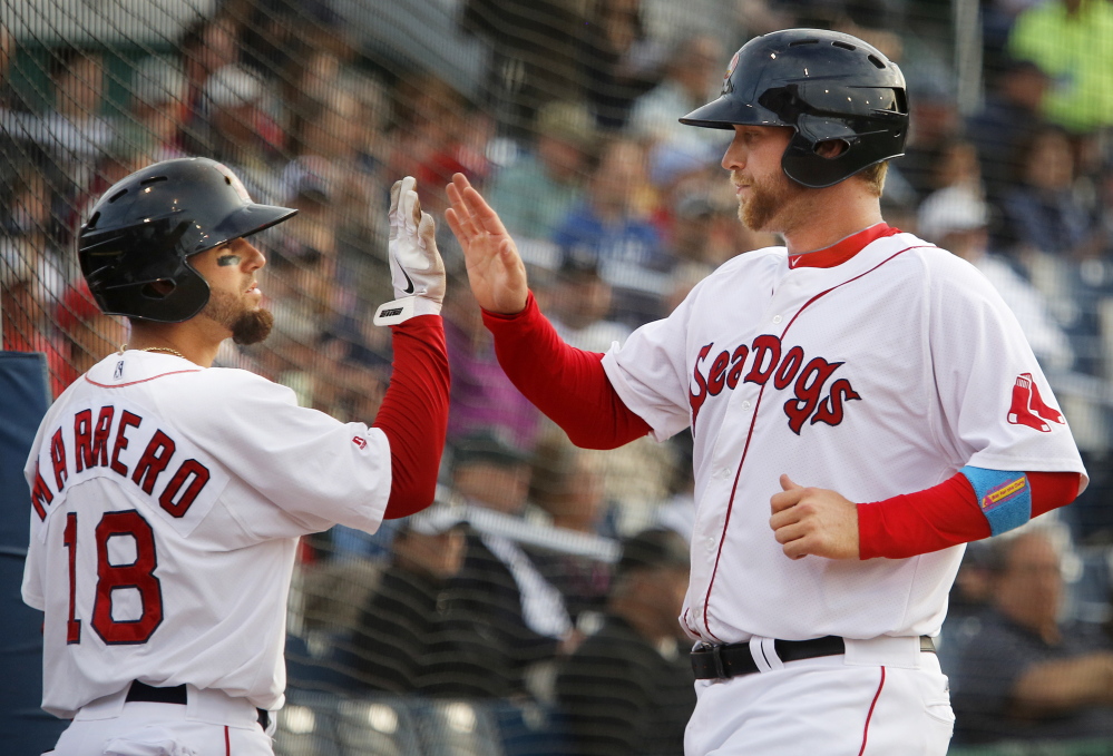 Dave Chester of the Portland Sea Dogs, right, is welcomed Monday night by Deven Marrero after scoring on a single by Heiker Meneses in the second inning of a 3-2 victory against the New Hampshire Fisher Cats at Hadlock Field. The Sea Dogs reached 50 wins and continue to hold a six-game lead over Binghamton in the division.