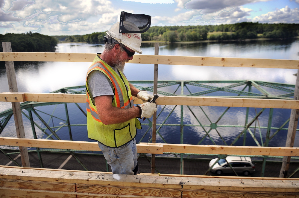 Reed & Reed Inc. worker Bob St. Pierre clips a piece of wire to secure reinforcing steel on the deck of the new bridge the firm is constructing over the Kennebec River between Richmond and Dresden. Tom Reed, who is overseeing the project for the Woolwich company, said he hopes to have the bridge open by Thanksgiving. Crews will then begin to disassemble the old swing bridge below.