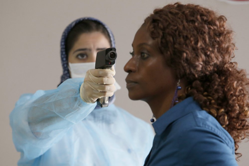 A Moroccan health worker uses a thermometer to screen a passenger at the arrivals hall of the Mohammed V airport in Casablanca, on Thursday. Airline passengers arriving in the U.S. from three West African countries will face temperature checks using no-touch thermometers and other screening measures at five American airports, starting with New York’s Kennedy on Saturday.