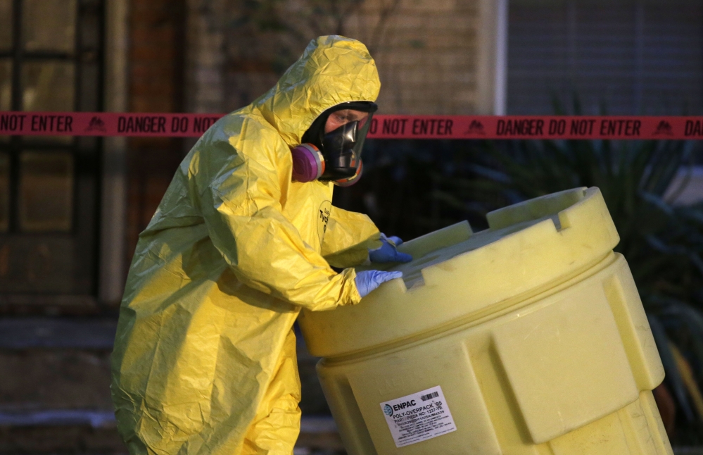 A hazmat worker moves a barrel while finishing up cleaning outside an apartment building of a hospital worker Sunday  in Dallas. The Texas health care worker, who was in full protective gear when they provided hospital care for Ebola patient Thomas Eric Duncan, who later died, has tested positive for the virus and is in stable condition, health officials said Sunday. The Associated Press