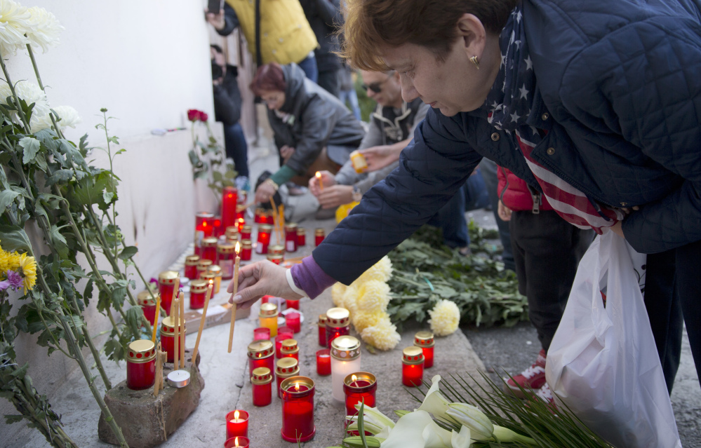 A woman lights candles outside the compound that housed the nightclub where a fire occurred in the early morning hours in Bucharest, Romania, on Saturday.