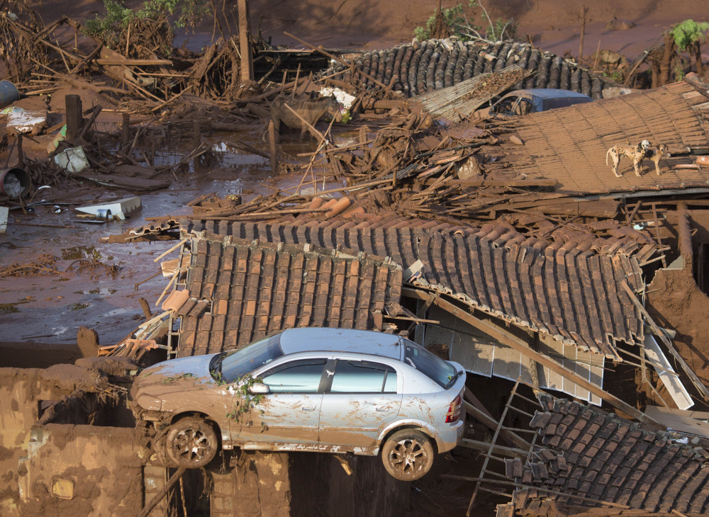A car and two dogs are seen Friday on the roofs of destroyed houses in the village of Bento Rodrigues, Brazil, after two dams belonging to an iron ore mine burst Thursday.