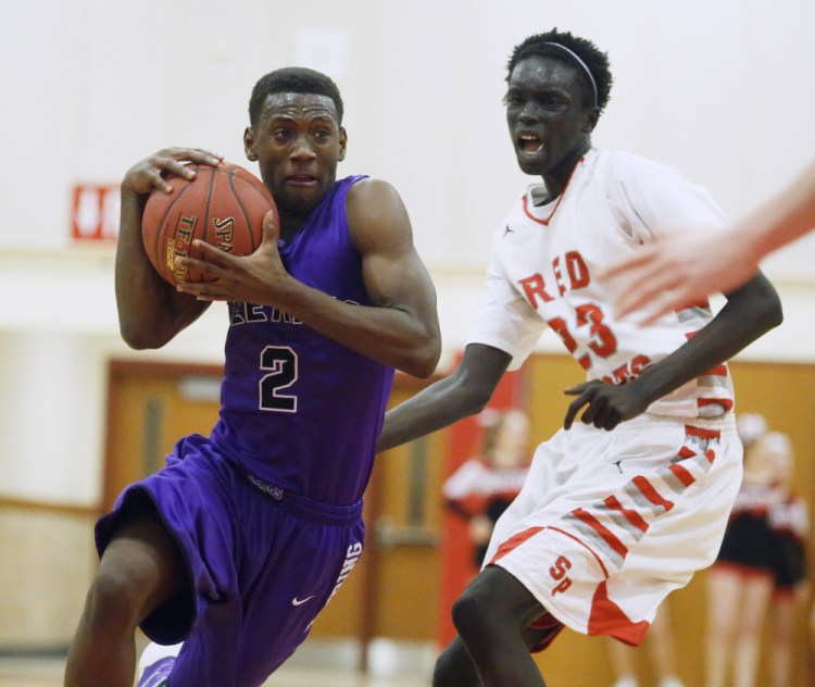 Jean Claude Butera of Deering heads to the basket as Ruay Bol of South Portland defends. Deering pulled away in the fourth quarter to remain undefeated.