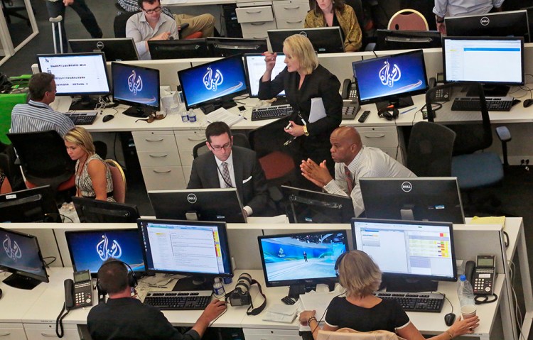 Al-Jazeera America editorial newsroom staff prepare for their first broadcast in New York on Aug. 20, 2013. The network says it will stop operating by April 30, blaming the “economic landscape of the media environment.”  File Photo/The Associated Press