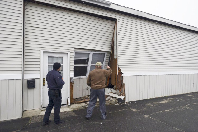 Property manager Joe Wojcik, right, looks over the damage with a city inspector after a vehicle crashed into a building on Forest Avenue in Portland on Tuesday.