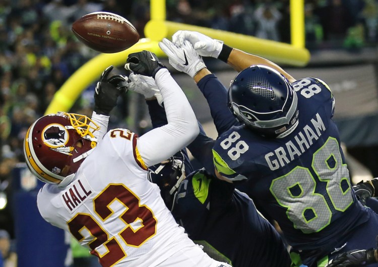 Washington safety DeAngelo Hall breaks up a Hail Mary pass against Jimmy Graham, right, and Tanner McEvoy of the Seahawks on the final play of a 17-14 win Sunday in Seattle.