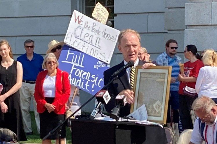 Jefferson E. Davis, spokesman for a group pushing for a broad review of the 2020 presidential election in Wisconsin, holds up a copy of the Declaration of Independence before leading a group of about 100 people into the state Capitol offices of Republican state leaders asking them to sign subpoenas for access to voting machines, ballots and other election material, on Sept. 10 in Madison, Wis.